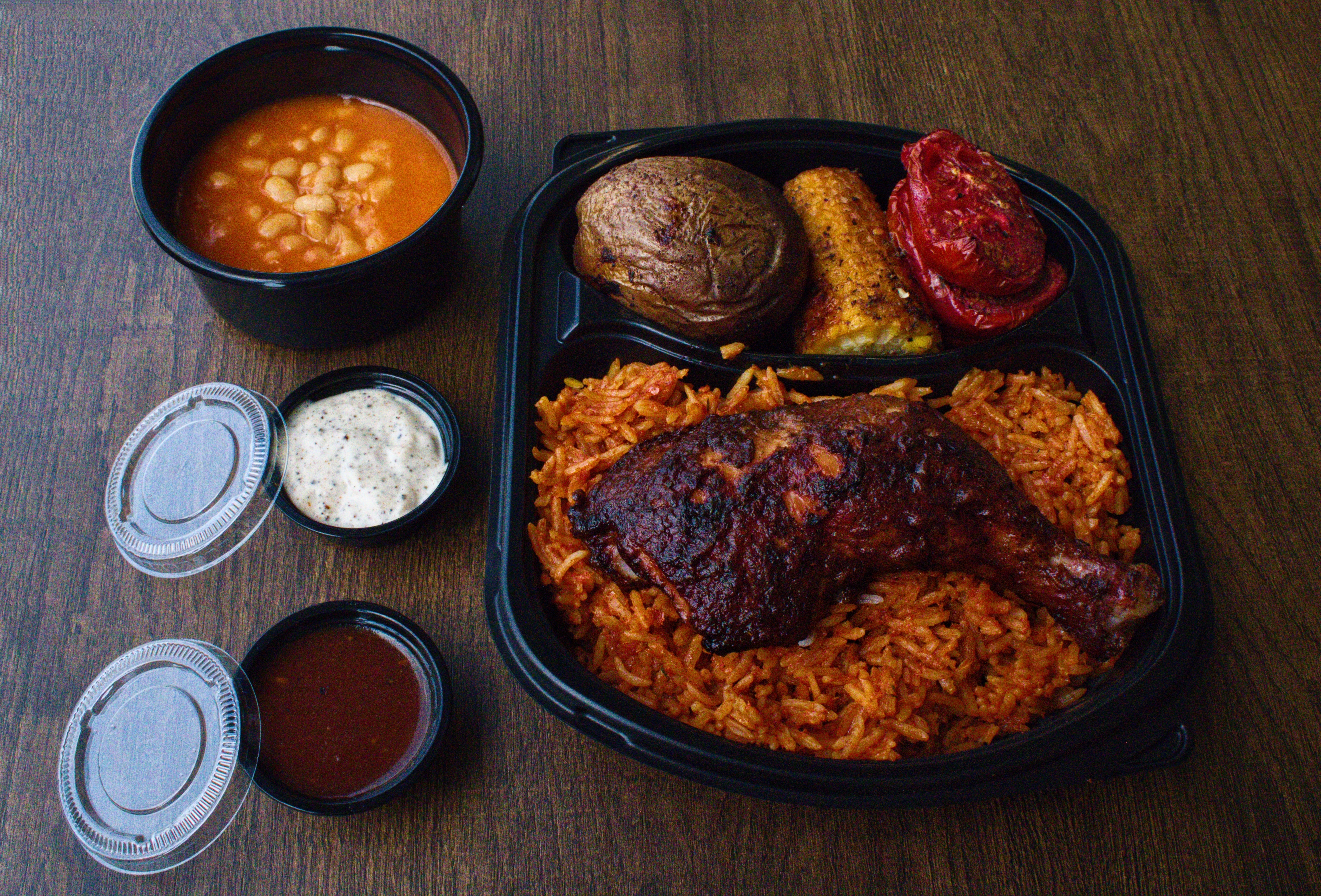 Smoked chicken thigh over red rice with roasted potato, corn, and tomato